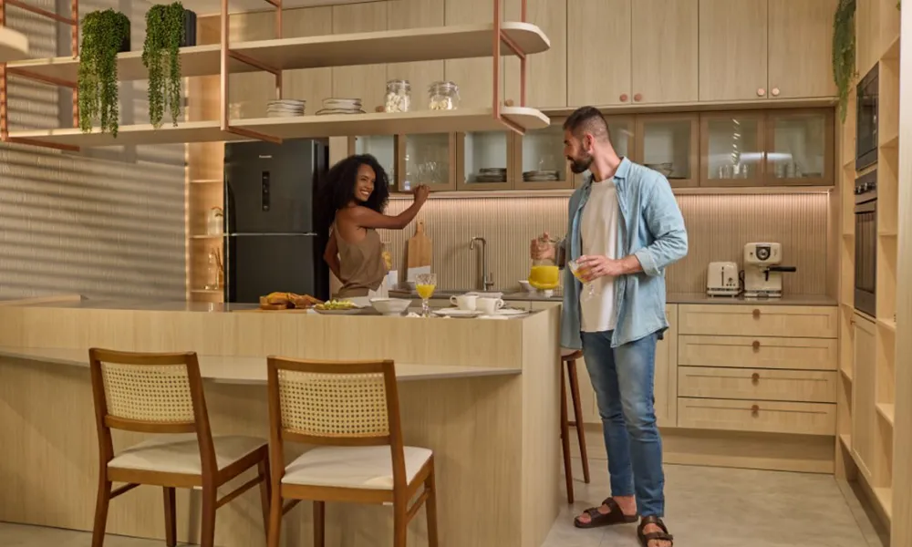 Cozinha planejada em tons claros com duas pessoas sorrindo