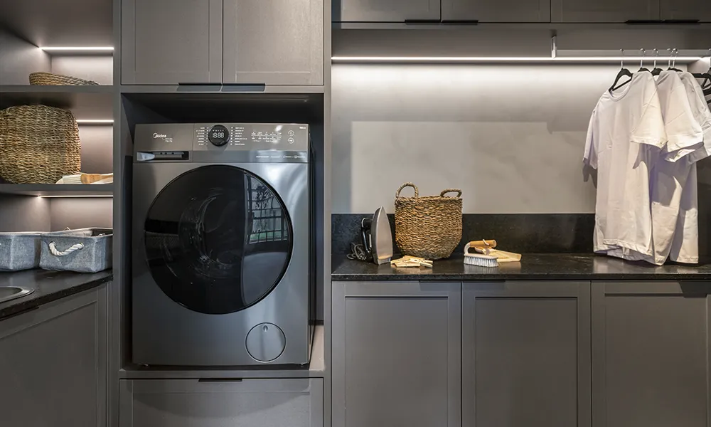 Lavanderia com máquina de lavar roupas e camisetas brancas penduradas