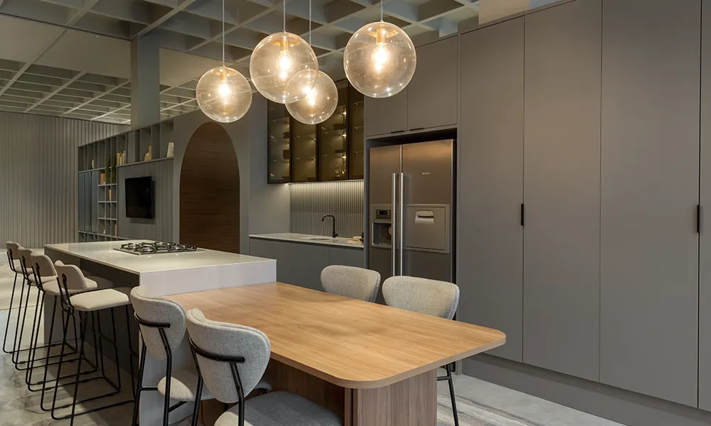 Cozinha planejada em tons de cinza com geladeira, bancada e mesa de jantar.