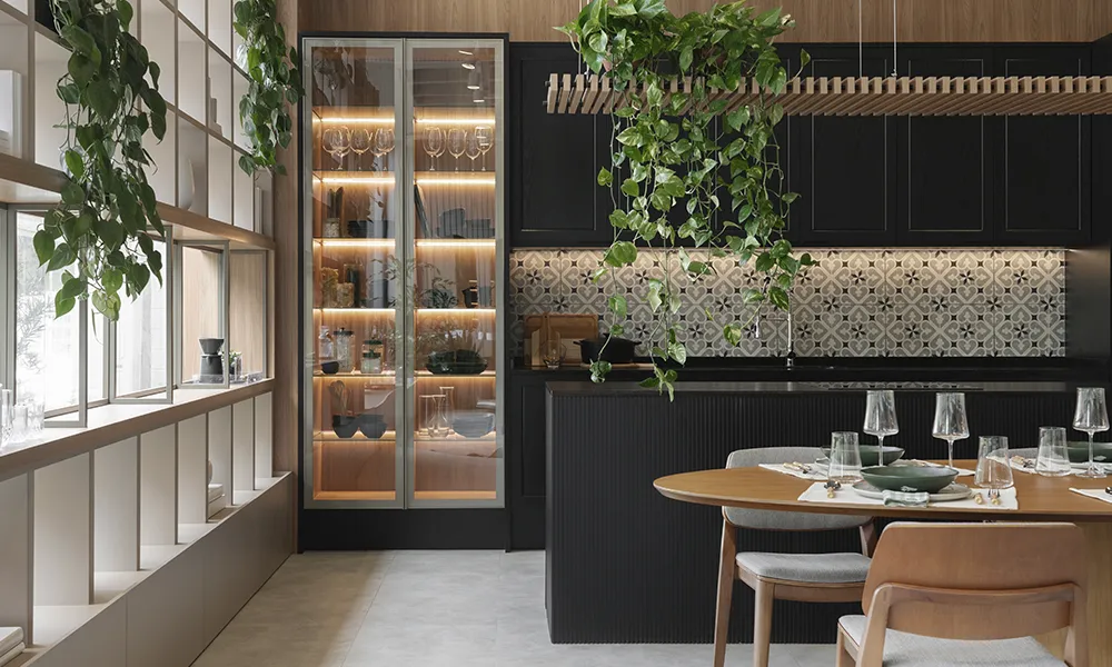 Cozinha na cor preta com cristaleira, plantas e mesa de jantar